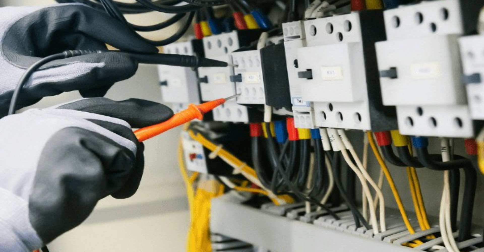 Elektrik panosunda multimetreyle ölçüm yapan teknisyen